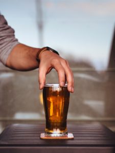 man picking up a glass of beer